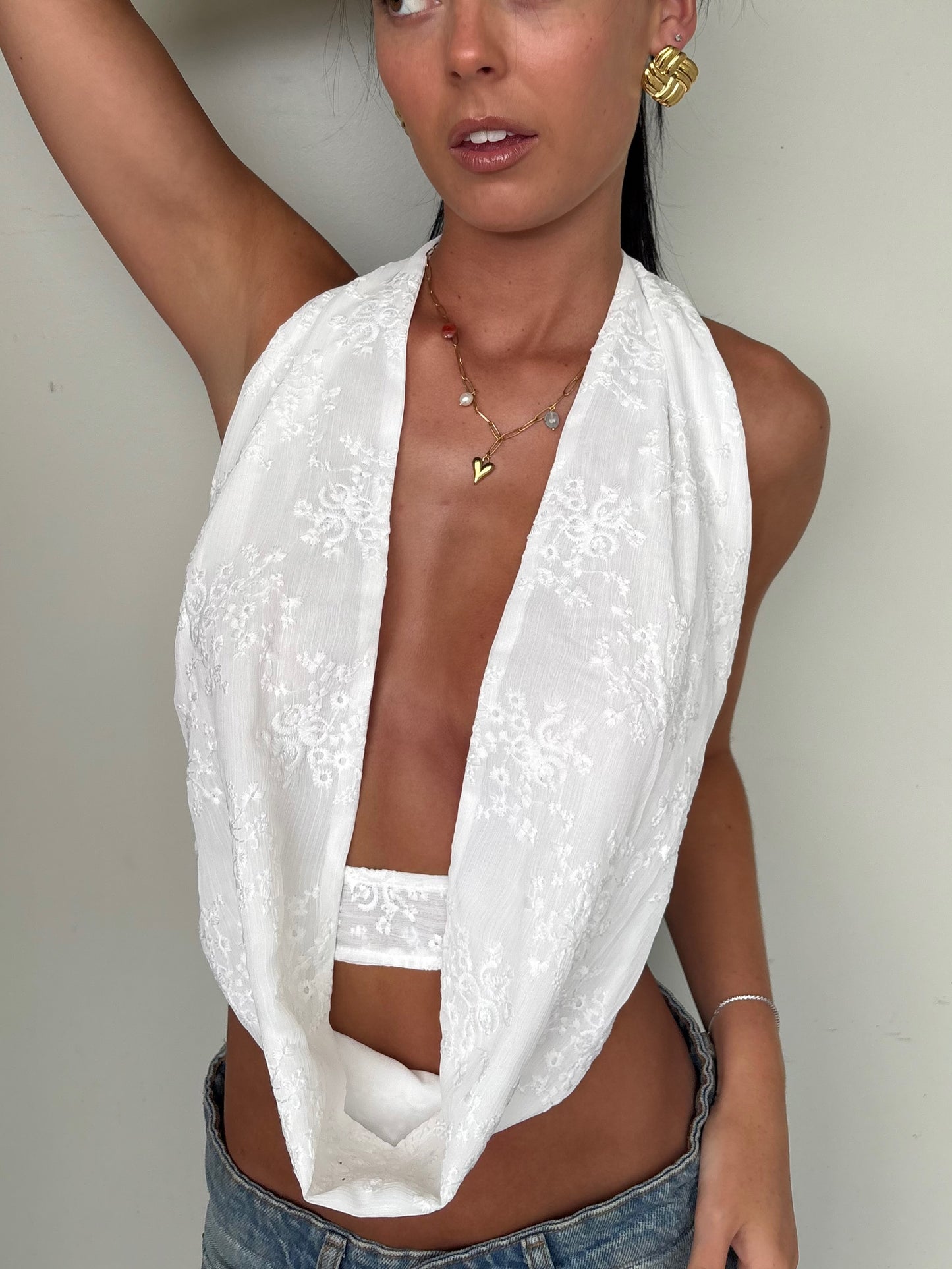 Model wearing a white scoop neck top from Yasmin The Label featuring adjustable ties at the top and back; clean minimalist design shown on model who is a size 6 and wears XS/S.