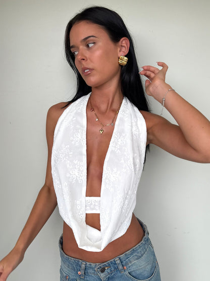 Model wearing a white scoop neck top from Yasmin The Label featuring adjustable ties at the top and back; clean minimalist design shown on model who is a size 6 and wears XS/S.